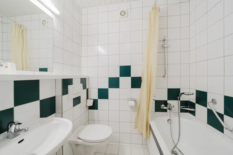 Bathroom with bathtub and green-and-white tiles in the Double Room with Private Garage at Motel Baden