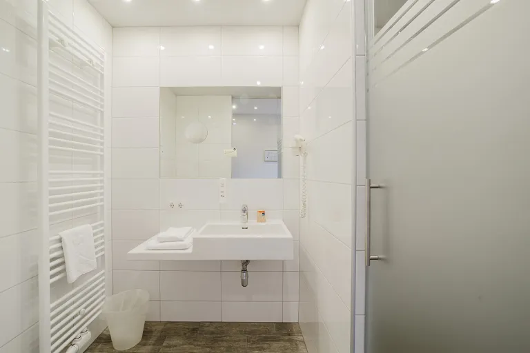 Bathroom with glass door, washbasin, and towel radiator at Motel Baden