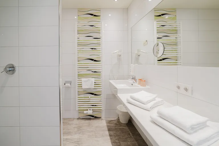 Bathroom with vanity, towels, and mosaic tiles at Motel Baden