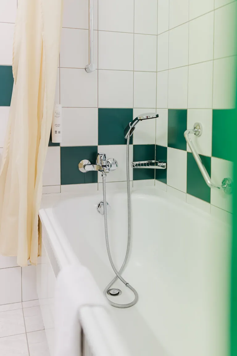 Bathtub in the green-and-white tiled bathroom at Motel Baden