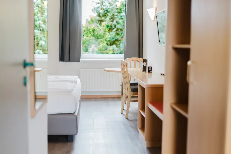 Double room with bed, shelving, and a view of greenery at Motel Baden