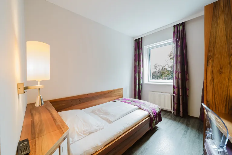 Bed with reading lamp by the window at Motel Baden