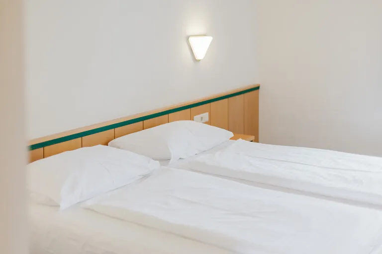 Freshly made bed with wall light at Motel Baden