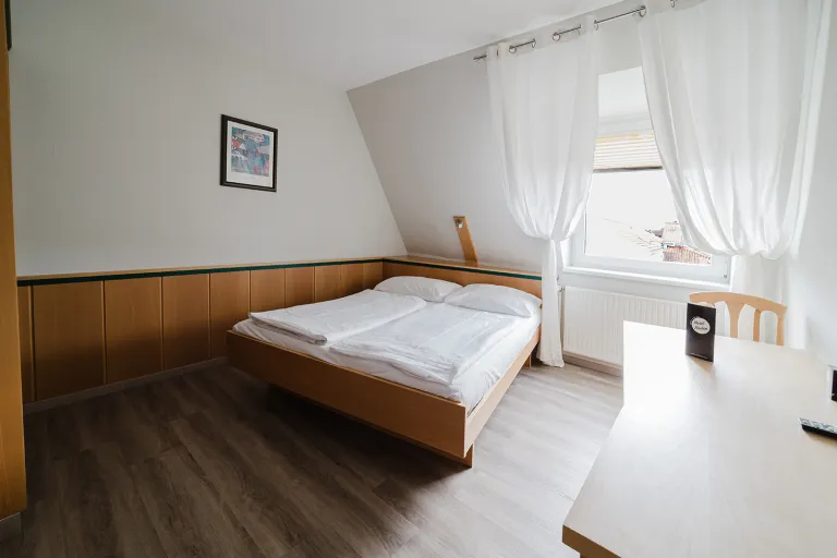 Double bed under the sloping roof by the window at Motel Baden