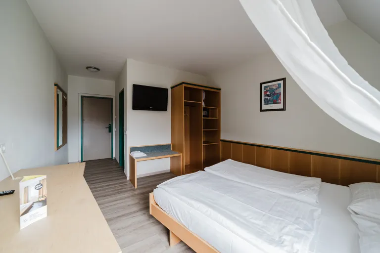Attic double room with bed, wardrobe and flat-screen TV at Motel Baden