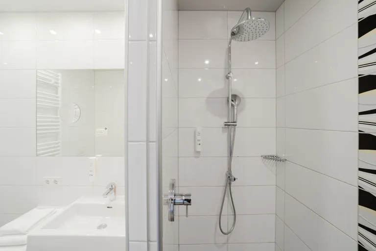 Shower with decorative tiles in the bathroom at Motel Baden
