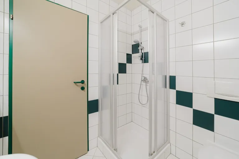 Shower cabin in the green-and-white tiled bathroom at Motel Baden
