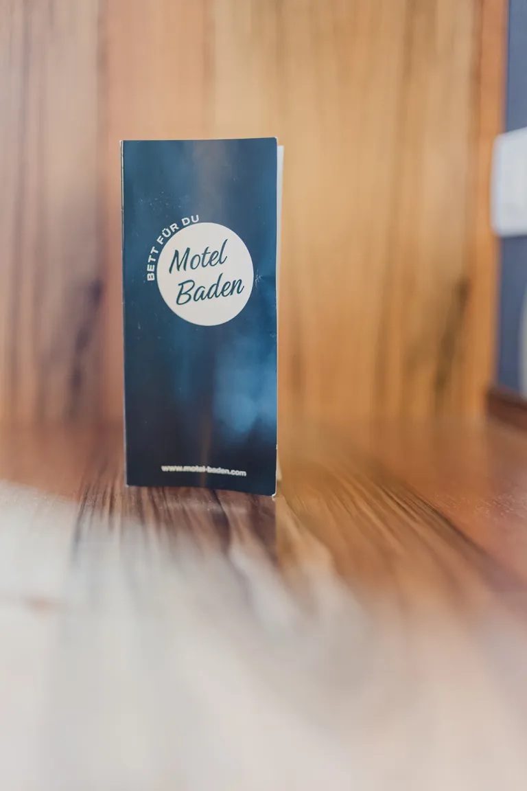 Motel Baden flyer in front of a wooden wall