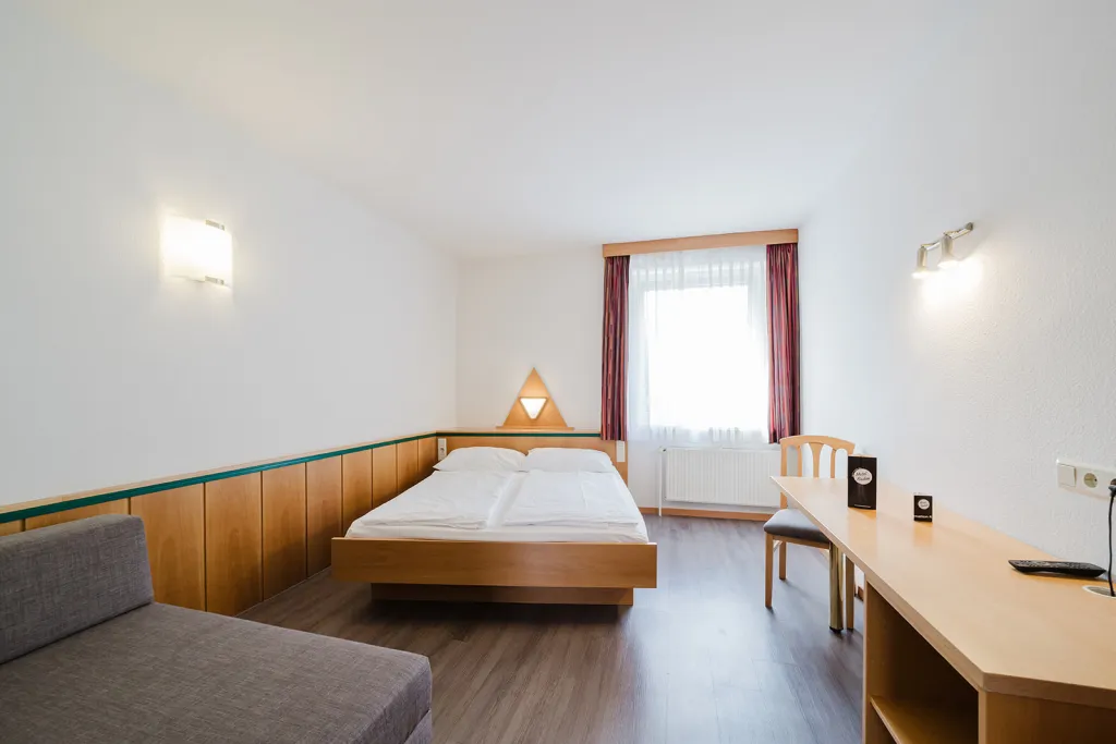 Room above the garage with double bed, seating area, and desk at Motel Baden