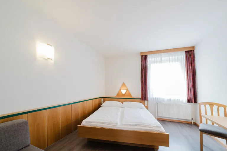 Double bed by the window in the double room with private garage at Motel Baden