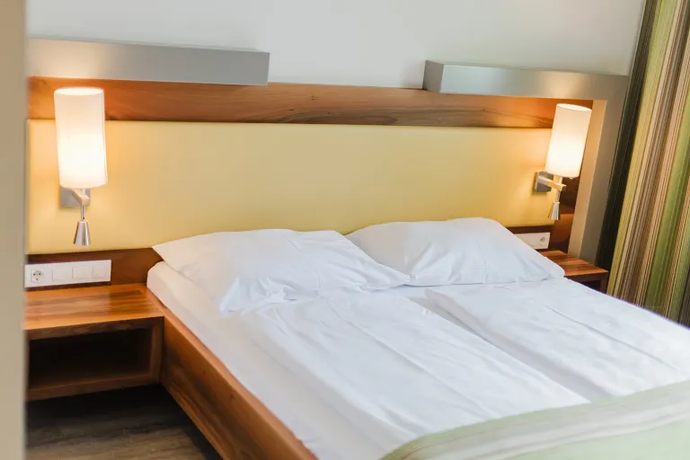 Double bed in front of a yellow wall with reading lamps at Motel Baden