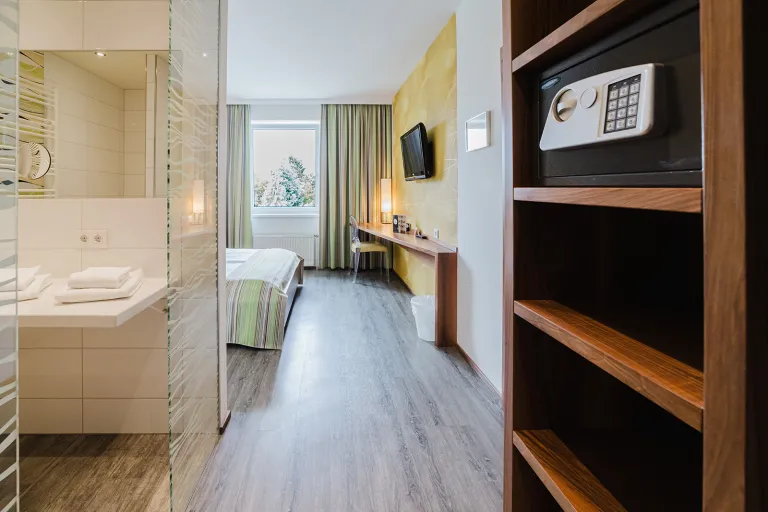 Double room with shelving, safe and open bathroom area at Motel Baden