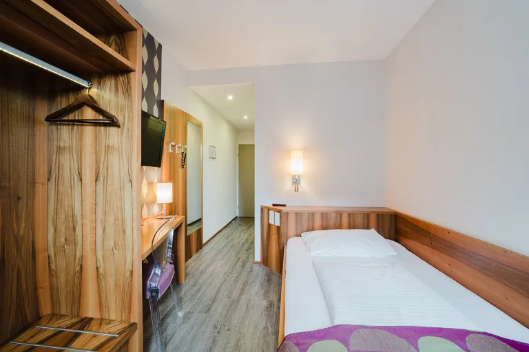 Single room with bed and wooden wardrobe at Motel Baden