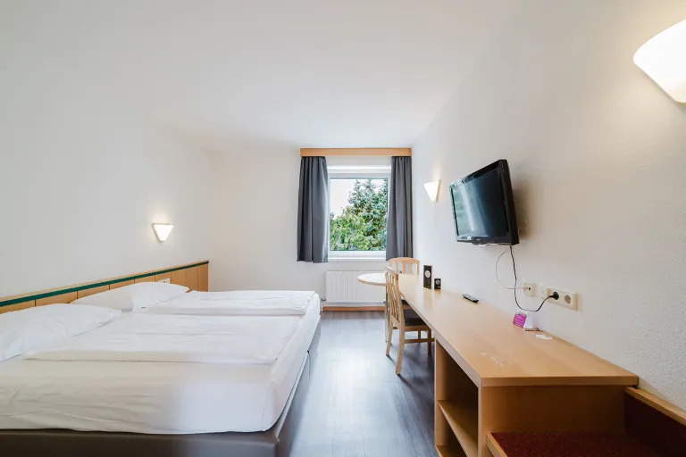 Modern double room with double bed, flat-screen TV and desk at Motel Baden