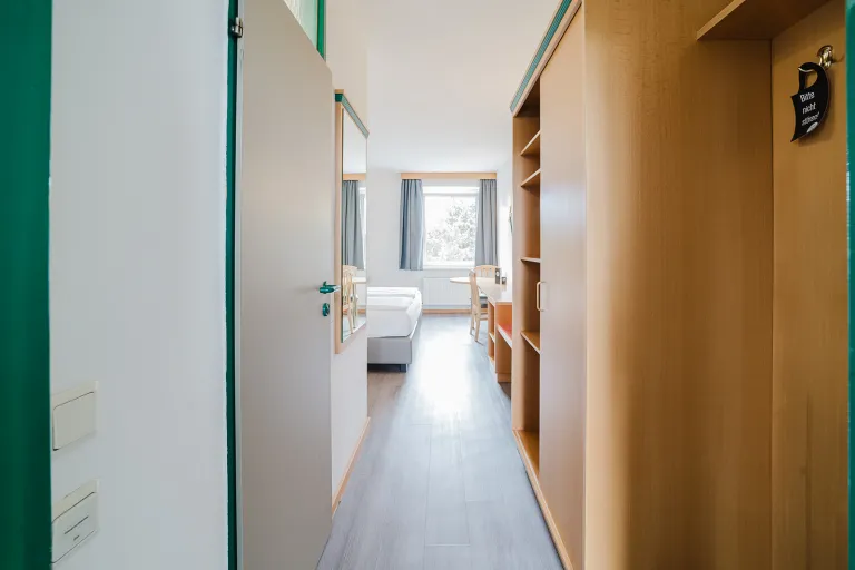 Modern double room with coat rack and view towards the window at Motel Baden