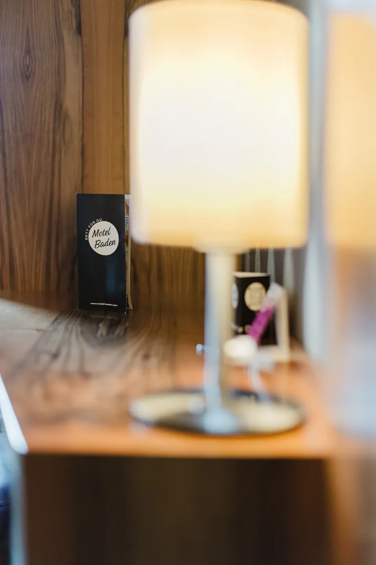 Bedside lamp with flyer at Motel Baden