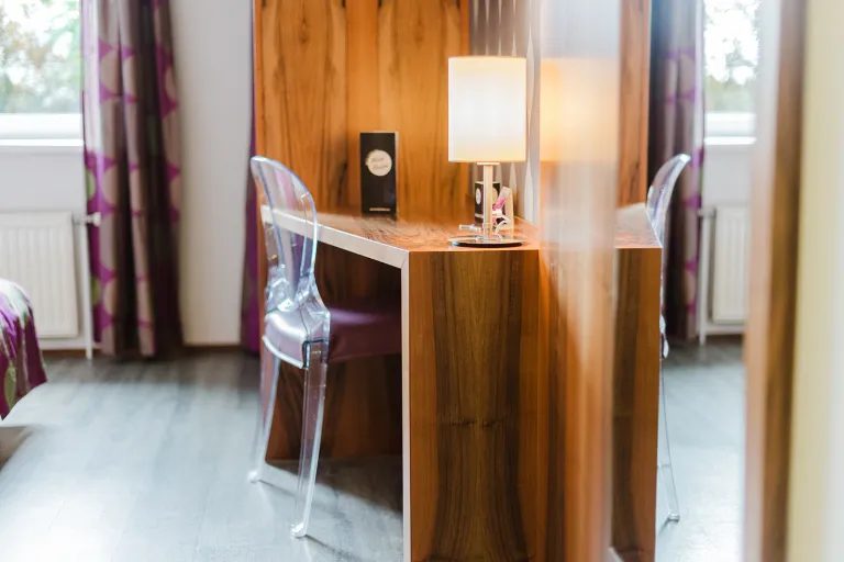 Desk with lamp and transparent chair at Motel Baden