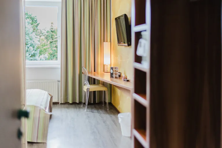 Double room with desk, window and shelving at Motel Baden