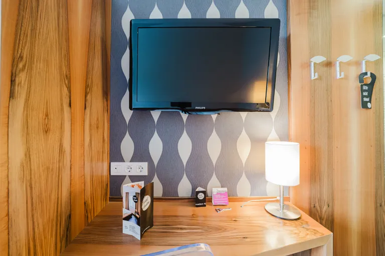 Desk with lamp and flat-screen TV at Motel Baden