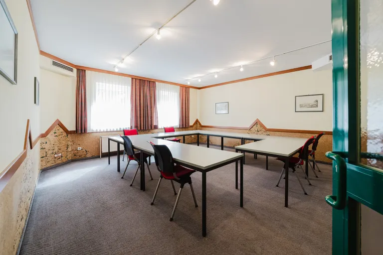 Small seminar room on the ground floor with tables and chairs at Motel Baden