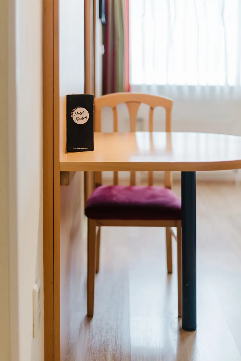 Table with chair and info flyer in a room at Motel Baden