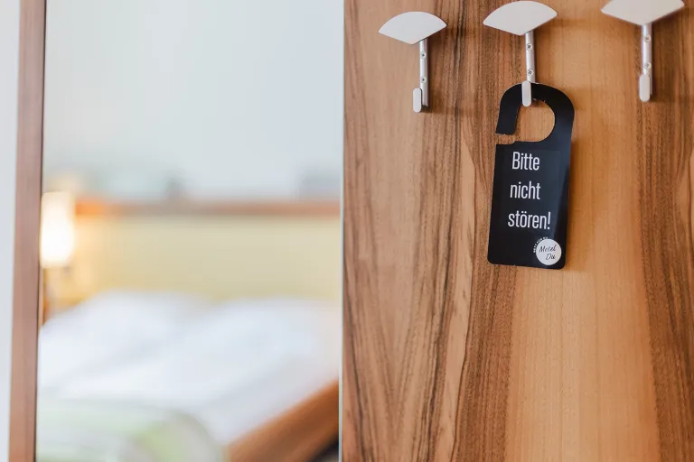 Door hanger on the coat rack, bed in the background at Motel Baden