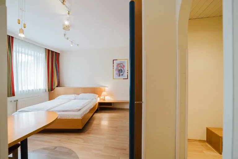 View through the connecting door into the room with double bed at Motel Baden