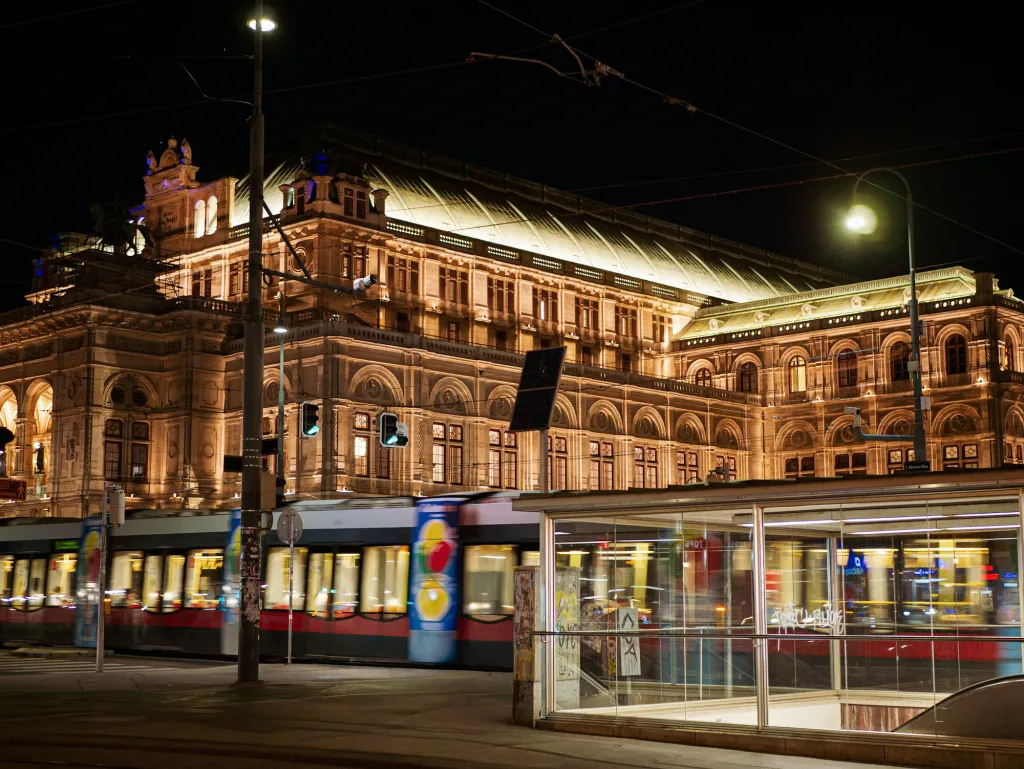 Beleuchtete Wiener Staatsoper mit Straßenbahn bei Nacht