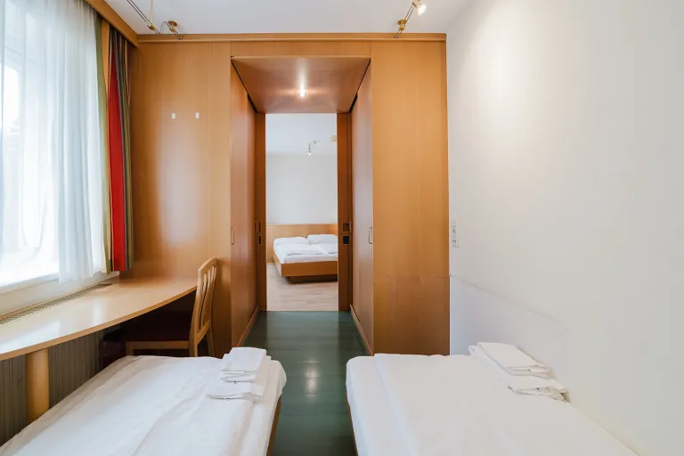Two single beds, desk, and passage at Motel Baden